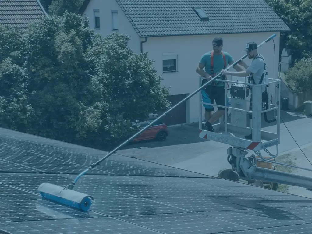 Zwei Solarreiniger Spezialisten reinigen eine PV-Anlage mit einer Teleskopbürste
