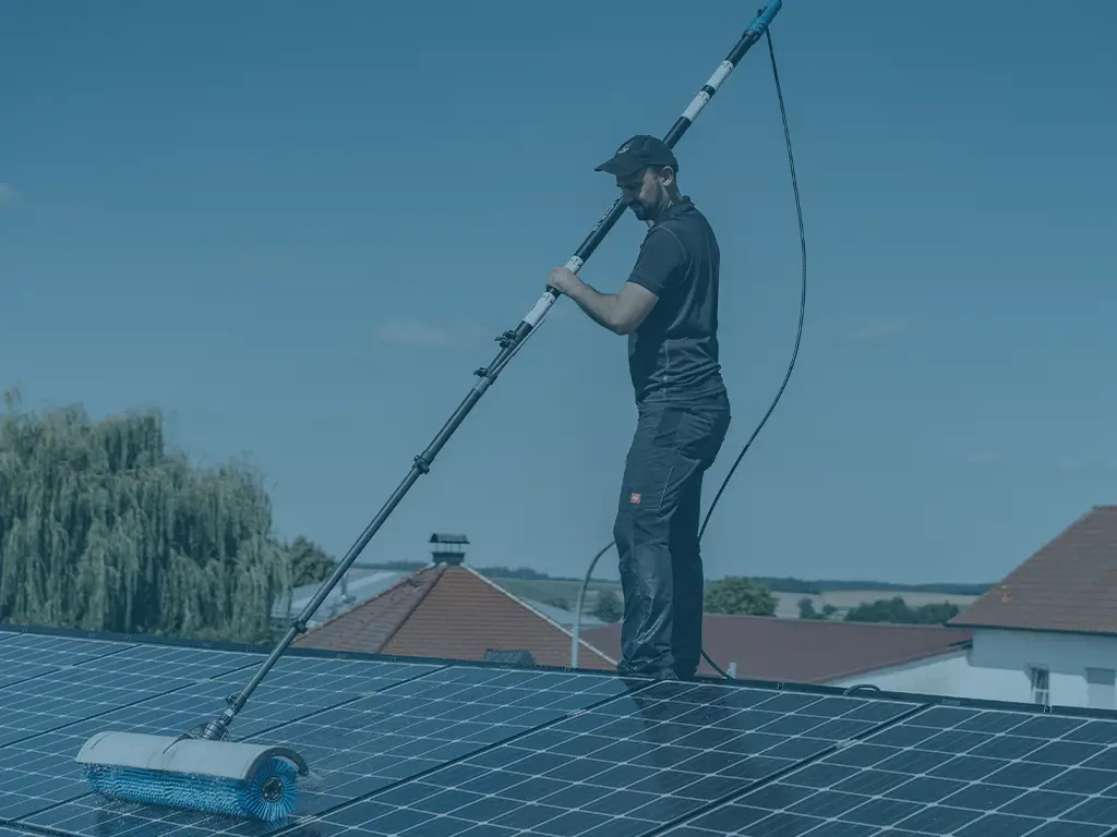 Ein Solarreiniger Spezialist reinigt eine PV-Anlage mit einer Teleskopbürste